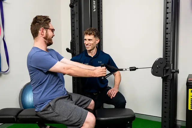 A clinician supervising a seated cable exercise